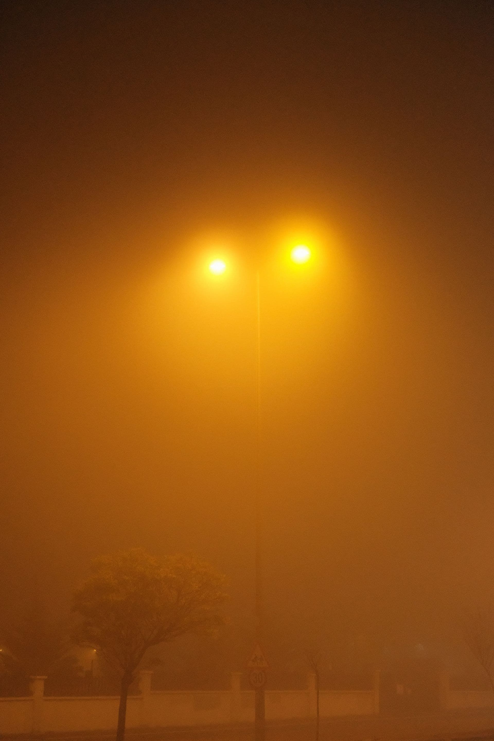 Streetlights glow through thick mist